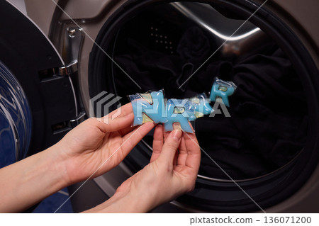 Preparing laundry with ecofriendly capsule, Man placing detergent pod into frontload washer quickly, Homeowner readying machine for eco washing in modern laundry area 136071200