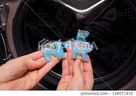 Preparing laundry with ecofriendly capsule, Man placing detergent pod into frontload washer quickly, Homeowner readying machine for eco washing in modern laundry area Preparing laundry with ecofriendly capsule, Man placing detergent pod into frontload washer quickly, Homeowner readying machine for eco washing in modern laundry area 136071438