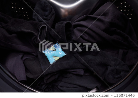 Preparing laundry with ecofriendly capsule, Man placing detergent pod into frontload washer quickly, Homeowner readying machine for eco washing in modern laundry area 136071446