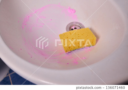 Homeowner prepares tub thoroughly, Closeup of hand cleaning soap scum from bathtub drain, Detailed view of person sanitizing bathtub with pink foam sponge and yellow glove 136071460