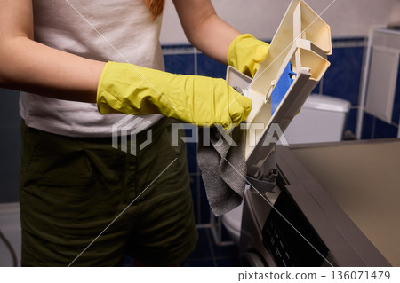 Checking detergent drawer for residue, Detailed view of appliance maintenance steps, Closeup of hands checking for limescale and residue in household appliance drawer Checking detergent drawer for residue, Detailed view of appliance maintenance steps, Closeup of hands checking for limescale and residue in household appliance drawer 136071479