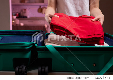 Organizing clothes before travel, Traveler arranges garments meticulously in their suitcase, An individual smoothly folds clothing and organizes suitcase for upcoming departure 136071524