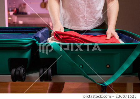 Organizing clothes before travel, Traveler arranges garments meticulously in their suitcase, An individual smoothly folds clothing and organizes suitcase for upcoming departure Organizing clothes before travel, Traveler arranges garments meticulously in their suitcase, An individual smoothly folds clothing and organizes suitcase for upcoming departure 136071525