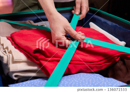 Adjusting luggage straps for safe travel, Careful setup of travel gear with strap focus, Ensuring secure strap positioning inside luggage before beginning your journey Adjusting luggage straps for safe travel, Careful setup of travel gear with strap focus, Ensuring secure strap positioning inside luggage before beginning your journey 136071533