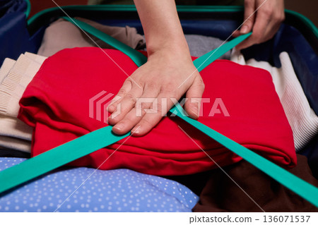 Adjusting luggage straps for safe travel, Careful setup of travel gear with strap focus, Ensuring secure strap positioning inside luggage before beginning your journey 136071537