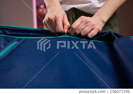 Organizing travel essentials, Meticulous placement of clothes within compact luggage for trip, Neatly organizing clothing and accessories in small bag for professional travel 136071546