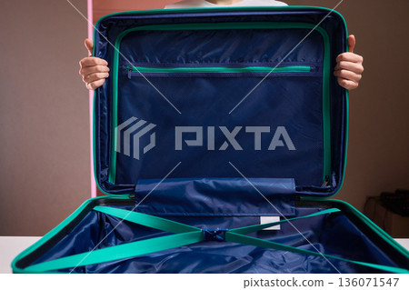 Organizing travel essentials, Meticulous placement of clothes within compact luggage for trip, Neatly organizing clothing and accessories in small bag for professional travel 136071547