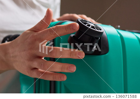 Inspecting suitcase wheels for strength and smooth operation before travel, Traveler thoroughly assesses condition and reliability of suitcase wheels for upcoming journey 136071588