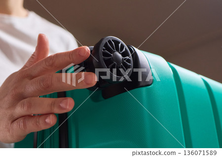 Inspecting suitcase wheels for strength and smooth operation before travel, Traveler thoroughly assesses condition and reliability of suitcase wheels for upcoming journey 136071589
