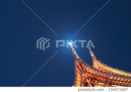 The roof of a traditional building shines in the moonlight. Looking up at the oriental aesthetic sense The roof of a traditional building shines in the moonlight. Looking up at the oriental aesthetic sense 136071807