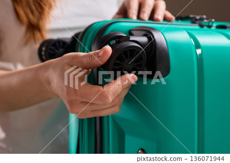 Inspecting suitcase wheels for strength and smooth operation before travel, Traveler thoroughly assesses condition and reliability of suitcase wheels for upcoming journey Inspecting suitcase wheels for strength and smooth operation before travel, Traveler thoroughly assesses condition and reliability of suitcase wheels for upcoming journey 136071944
