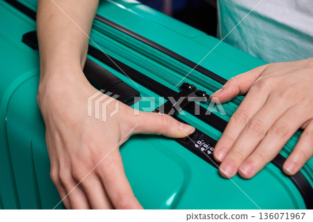 Secure suitcase with combo lock, Hands set combination on teal suitcase with textured surface, Closeup of hands adjusting numeric lock on stylish teal travel suitcase Secure suitcase with combo lock, Hands set combination on teal suitcase with textured surface, Closeup of hands adjusting numeric lock on stylish teal travel suitcase 136071967