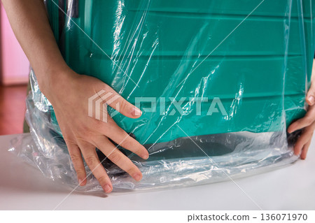 Luggage wrapping process, Worker securing suitcase with protective plastic film, Ensuring safety and protection through meticulous wrapping of belongings for travel Luggage wrapping process, Worker securing suitcase with protective plastic film, Ensuring safety and protection through meticulous wrapping of belongings for travel 136071970