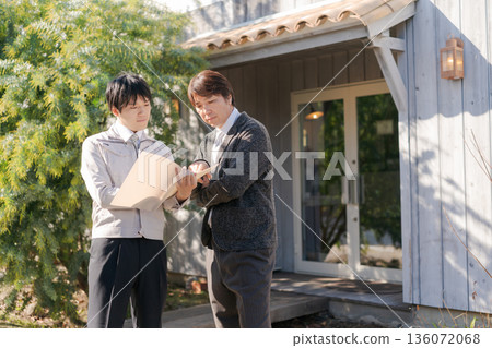 Men in work clothes talking in front of a stylish building 136072068