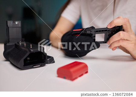Camera power supply setup process, Connecting battery pack carefully into camera housing for filming, Unboxing and installing power source into camera in studio setting Camera power supply setup process, Connecting battery pack carefully into camera housing for filming, Unboxing and installing power source into camera in studio setting 136072084