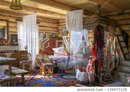 The interior of a 19th-century Russian hut with a bed and a cradle suspended from the ceiling 136072226