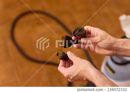 Household brushes examined closely, Two brushes analyzed in indoor setting, Person holding two black brushes inspecting bristle arrangement for household cleaning purposes Household brushes examined closely, Two brushes analyzed in indoor setting, Person holding two black brushes inspecting bristle arrangement for household cleaning purposes 136072332