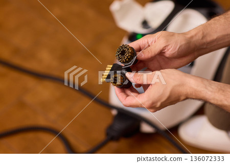Household brushes examined closely, Two brushes analyzed in indoor setting, Person holding two black brushes inspecting bristle arrangement for household cleaning purposes Household brushes examined closely, Two brushes analyzed in indoor setting, Person holding two black brushes inspecting bristle arrangement for household cleaning purposes 136072333
