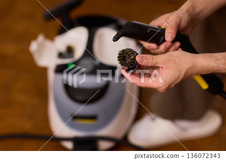 Household brushes examined closely, Two brushes analyzed in indoor setting, Person holding two black brushes inspecting bristle arrangement for household cleaning purposes Household brushes examined closely, Two brushes analyzed in indoor setting, Person holding two black brushes inspecting bristle arrangement for household cleaning purposes 136072343