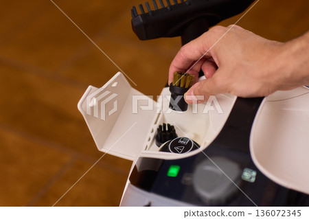 Household brushes examined closely, Two brushes analyzed in indoor setting, Person holding two black brushes inspecting bristle arrangement for household cleaning purposes 136072345