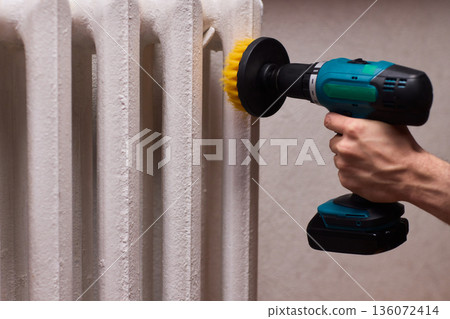 Radiator cleaning process, Metal radiator being cleaned with power brush in workshop, Effective deep cleaning of radiator using drill brush in home maintenance setting 136072414