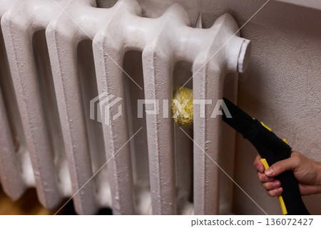 Brass brush during radiator cleaning, Closeup of hand using steam to clean radiator, Careful hand cleaning cast iron radiator with steam and brass brush in home environment Brass brush during radiator cleaning, Closeup of hand using steam to clean radiator, Careful hand cleaning cast iron radiator with steam and brass brush in home environment 136072427