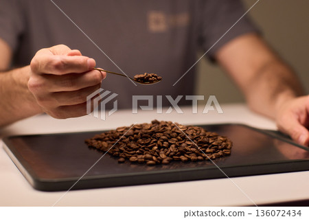 Detail oriented scene of coffee professional measuring beans carefully, An intimate scene depicting barista accurately measuring roasted coffee beans with gold scoop Detail oriented scene of coffee professional measuring beans carefully, An intimate scene depicting barista accurately measuring roasted coffee beans with gold scoop 136072434