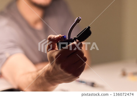 Closeup spark ignition, Gadget reviewer showcases plasma lighter in dim setting, Detailed view of ignition process using modern electronic device in cozy lighting environment 136072474
