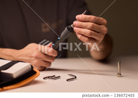 Precision soldering procedure, Hands meticulously align soldering tool precisely, Technician in closeup carefully adjusting soldering tip with safety and measurement focus Precision soldering procedure, Hands meticulously align soldering tool precisely, Technician in closeup carefully adjusting soldering tip with safety and measurement focus 136072485
