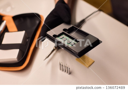 Detailed shot capturing repair process of computer memory components, Technician carefully handling SODIMM memory module while performing technical diagnostic procedures Detailed shot capturing repair process of computer memory components, Technician carefully handling SODIMM memory module while performing technical diagnostic procedures 136072489