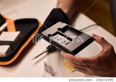Detailed shot capturing repair process of computer memory components, Technician carefully handling SODIMM memory module while performing technical diagnostic procedures Detailed shot capturing repair process of computer memory components, Technician carefully handling SODIMM memory module while performing technical diagnostic procedures 136072490