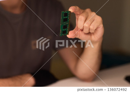 Individual carefully inspecting SODIMM memory module in detailed review, Technician performing detailed visual assessment of RAM stick with neutral lighting and focused attention Individual carefully inspecting SODIMM memory module in detailed review, Technician performing detailed visual assessment of RAM stick with neutral lighting and focused attention 136072492