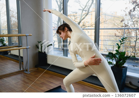 Woman performing side stretch exercise in yoga studio 136072607
