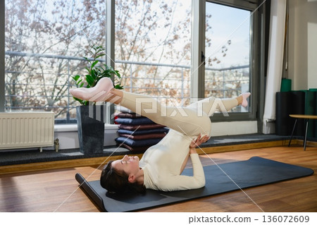 Woman practicing plow pose yoga exercise in studio Woman practicing plow pose yoga exercise in studio 136072609