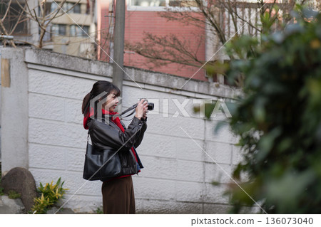A woman strolling around Shinjuku Arakicho with a camera 136073040