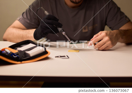 Detailed shot capturing repair process of computer memory components, Technician carefully handling SODIMM memory module while performing technical diagnostic procedures 136073067