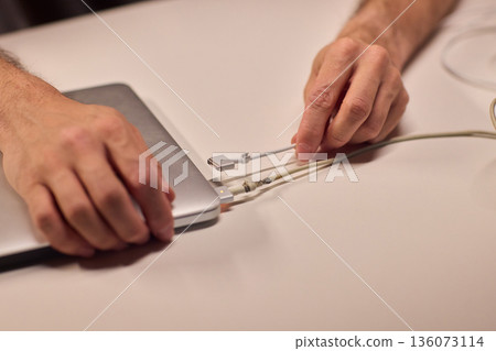 Repairing laptop power cord, Detailed image of fixing broken laptop charger wire, Closeup of skillful person restoring worn electrical cord for portable computer 136073114