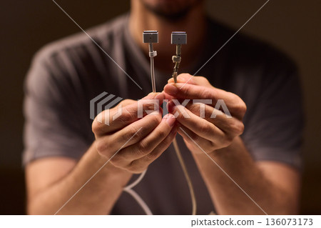 Repairing damaged cable, Hands carefully inspecting damaged laptop power cable insulation, Focused closeup of hands troubleshooting frayed wires and exposed copper connectors Repairing damaged cable, Hands carefully inspecting damaged laptop power cable insulation, Focused closeup of hands troubleshooting frayed wires and exposed copper connectors 136073173