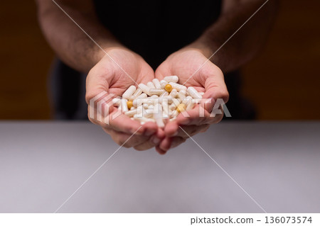 Closeup of caregiver preparing medication in warm bathroom environment, Wrist and fingers shown as caregiver arranges pills from bottle for daily dosage in soothing lighting Closeup of caregiver preparing medication in warm bathroom environment, Wrist and fingers shown as caregiver arranges pills from bottle for daily dosage in soothing lighting 136073574