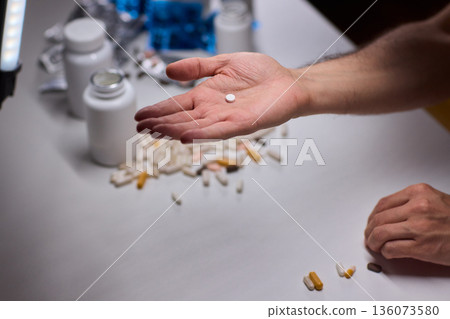 Anxious scene showing medication overload and health concerns, Clinical setting depicting patient holding pills surrounded by bottles indicating potential overdose 136073580