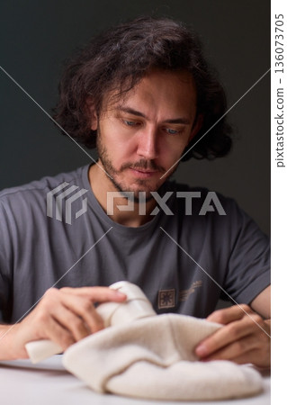 Close view of lint tool on wool, Man using lint roller to clean wool hat texture, Detailed scene of hand grooming fuzz from soft knitted wool hat with lint roller 136073705