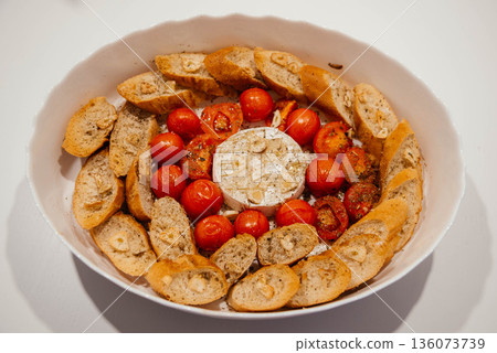 Camembert cheese baked with tomatoes and baguette, herbs and garlic. An excellent appetizer for wine. View from above.  136073739