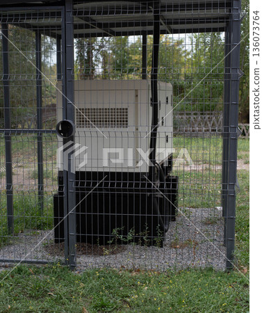 Installation of a large industrial fuel-fired generator on a green lawn. A mobile power source, backup equipment for power plants.  136073764