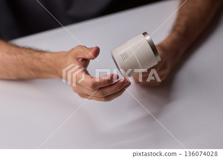 Close view of lint tool on wool, Man using lint roller to clean wool hat texture, Detailed scene of hand grooming fuzz from soft knitted wool hat with lint roller 136074028