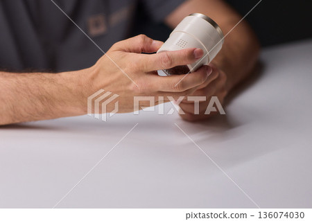 Close view of lint tool on wool, Man using lint roller to clean wool hat texture, Detailed scene of hand grooming fuzz from soft knitted wool hat with lint roller 136074030