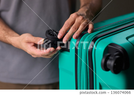 Inspecting suitcase wheels for strength and smooth operation before travel, Traveler thoroughly assesses condition and reliability of suitcase wheels for upcoming journey Inspecting suitcase wheels for strength and smooth operation before travel, Traveler thoroughly assesses condition and reliability of suitcase wheels for upcoming journey 136074066