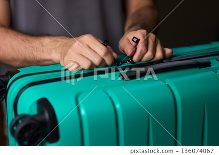 Secure suitcase with combo lock, Hands set combination on teal suitcase with textured surface, Closeup of hands adjusting numeric lock on stylish teal travel suitcase Secure suitcase with combo lock, Hands set combination on teal suitcase with textured surface, Closeup of hands adjusting numeric lock on stylish teal travel suitcase 136074067