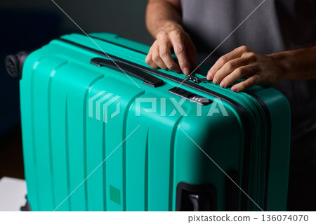 Secure suitcase with combo lock, Hands set combination on teal suitcase with textured surface, Closeup of hands adjusting numeric lock on stylish teal travel suitcase Secure suitcase with combo lock, Hands set combination on teal suitcase with textured surface, Closeup of hands adjusting numeric lock on stylish teal travel suitcase 136074070