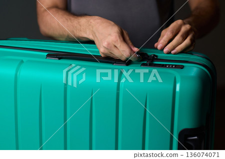 Secure suitcase with combo lock, Hands set combination on teal suitcase with textured surface, Closeup of hands adjusting numeric lock on stylish teal travel suitcase Secure suitcase with combo lock, Hands set combination on teal suitcase with textured surface, Closeup of hands adjusting numeric lock on stylish teal travel suitcase 136074071