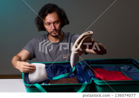 Organizing clothes before travel, Traveler arranges garments meticulously in their suitcase, An individual smoothly folds clothing and organizes suitcase for upcoming departure 136074077